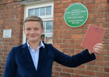 Student with Choyce's book of poetry in front of Green Plaque
