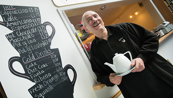 man holding a tea pot, standing in a coffee shop