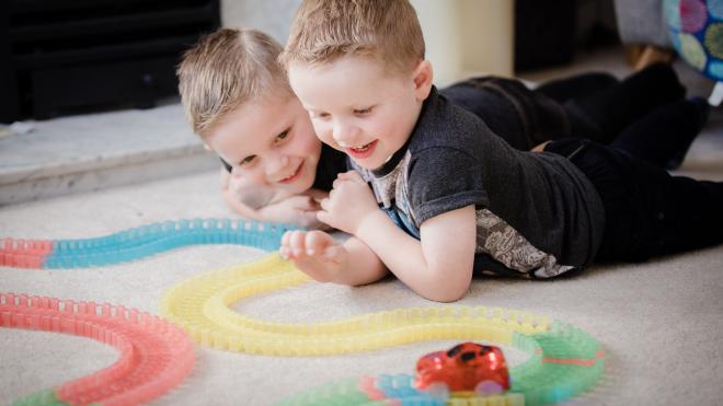 two boys playing with a train track