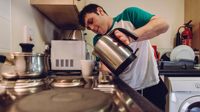 A young adult making a cup of tea