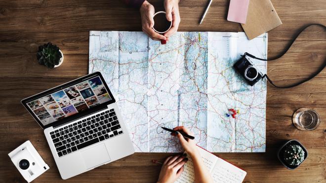 Holidaymakers urged to avoid booking fraud Planning holiday with a map and laptop