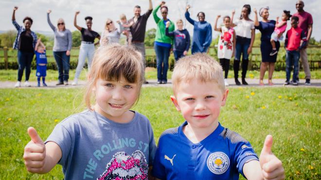 Young girl and boy with thumbs up in front of group