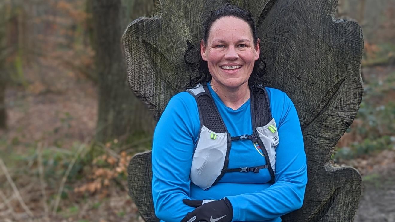 A person sitting on carved out chair in the woods