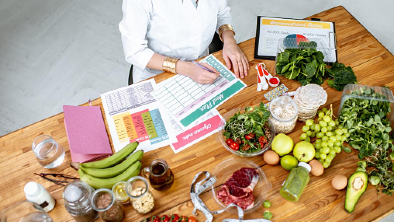 Weight Management Leicestershire a person sat at a table filled with fruits and vegetables filling in forms