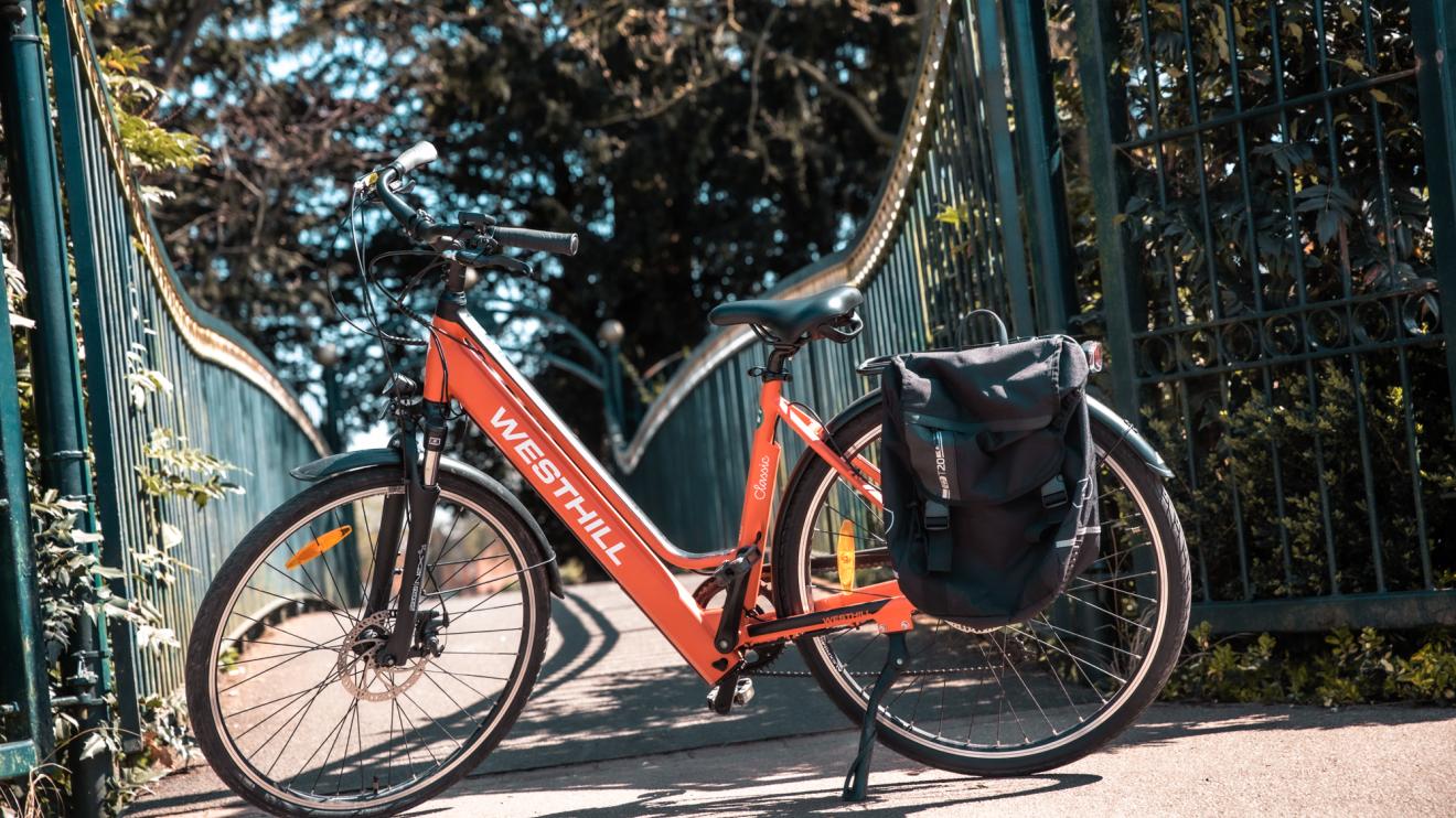An electric bike parked in front of a pedestrianised bridge with teal railings.