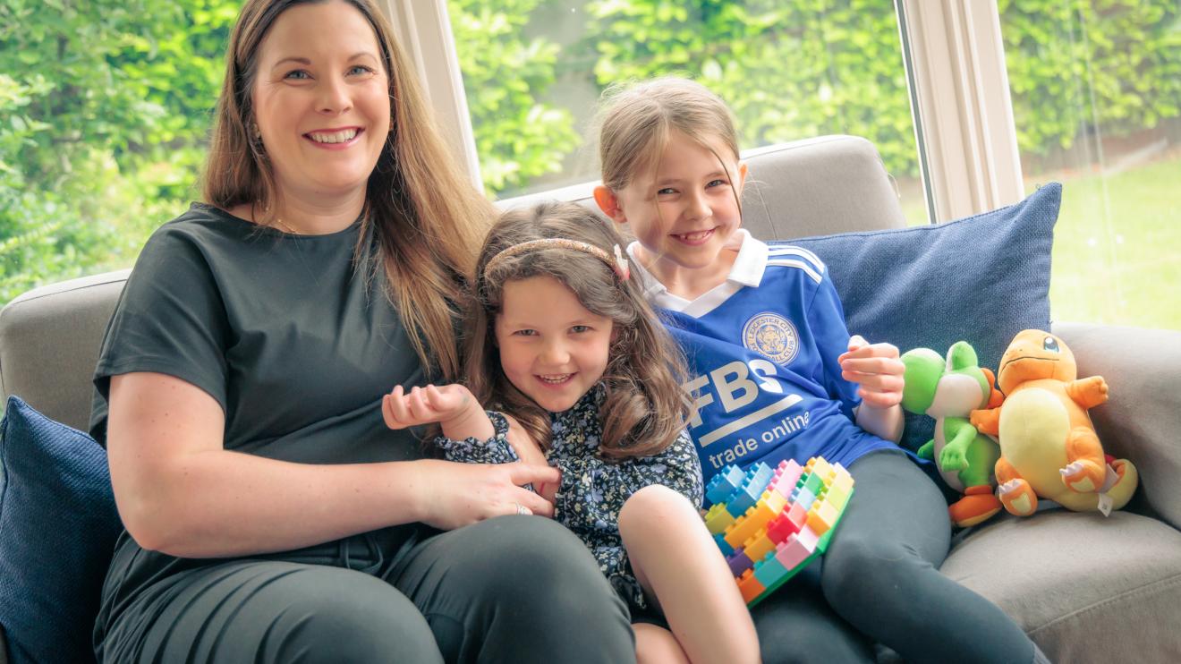 fostering family Smiling woman sat on a sofa with a young boy and a girl
