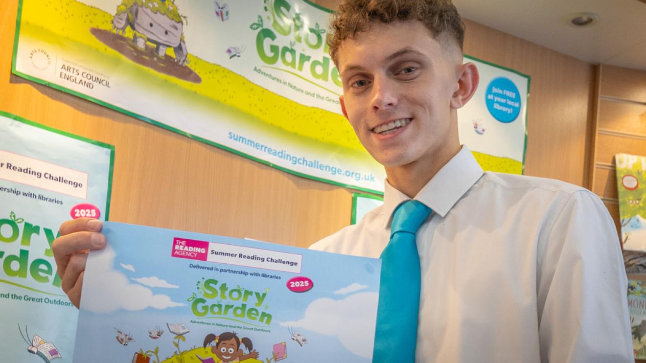 Councillor Joseph Boam with a poster for the summer reading challenge