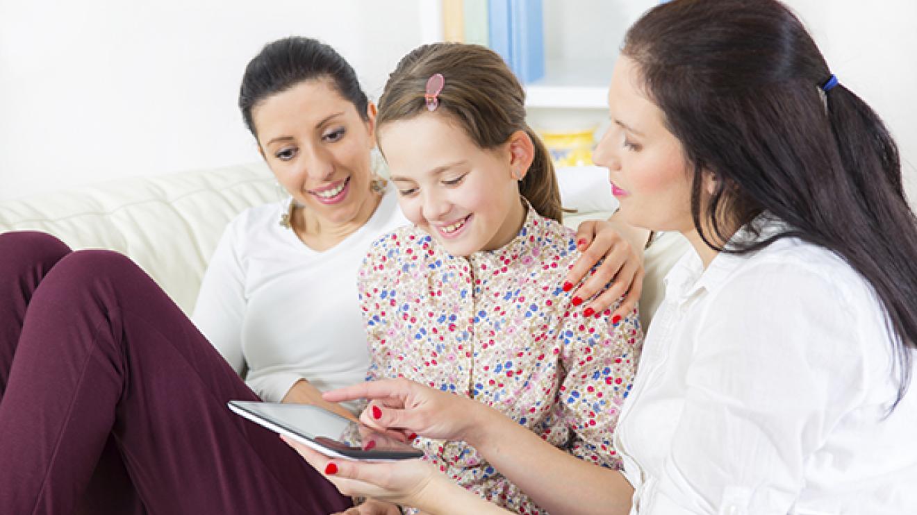 two ladies and a girl looking at a tablet device