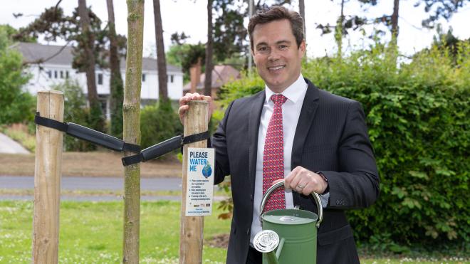 Councillor Blake Pain waters a young tree