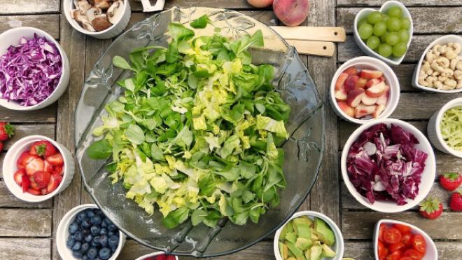 Bowl full of lettuce surrounded by smaller bowls of salad ingredients