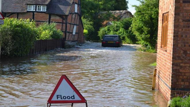 Flooded village with flood warning sign