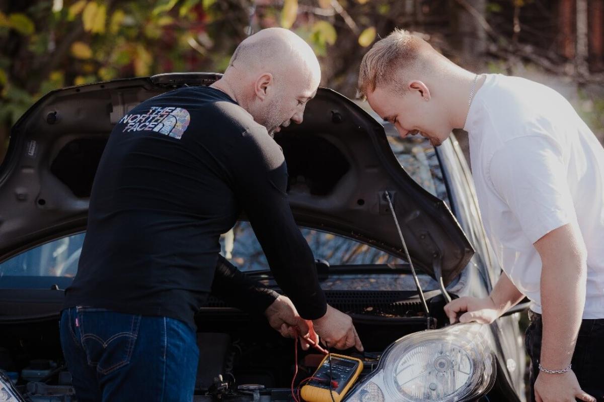 Foster carer and a young boy fixing a car together