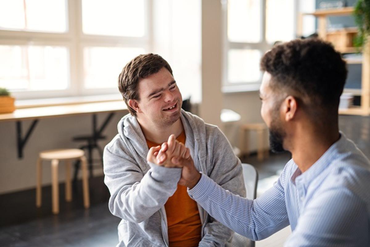 A person with Down's Syndrome holding hands with a carer and smiling