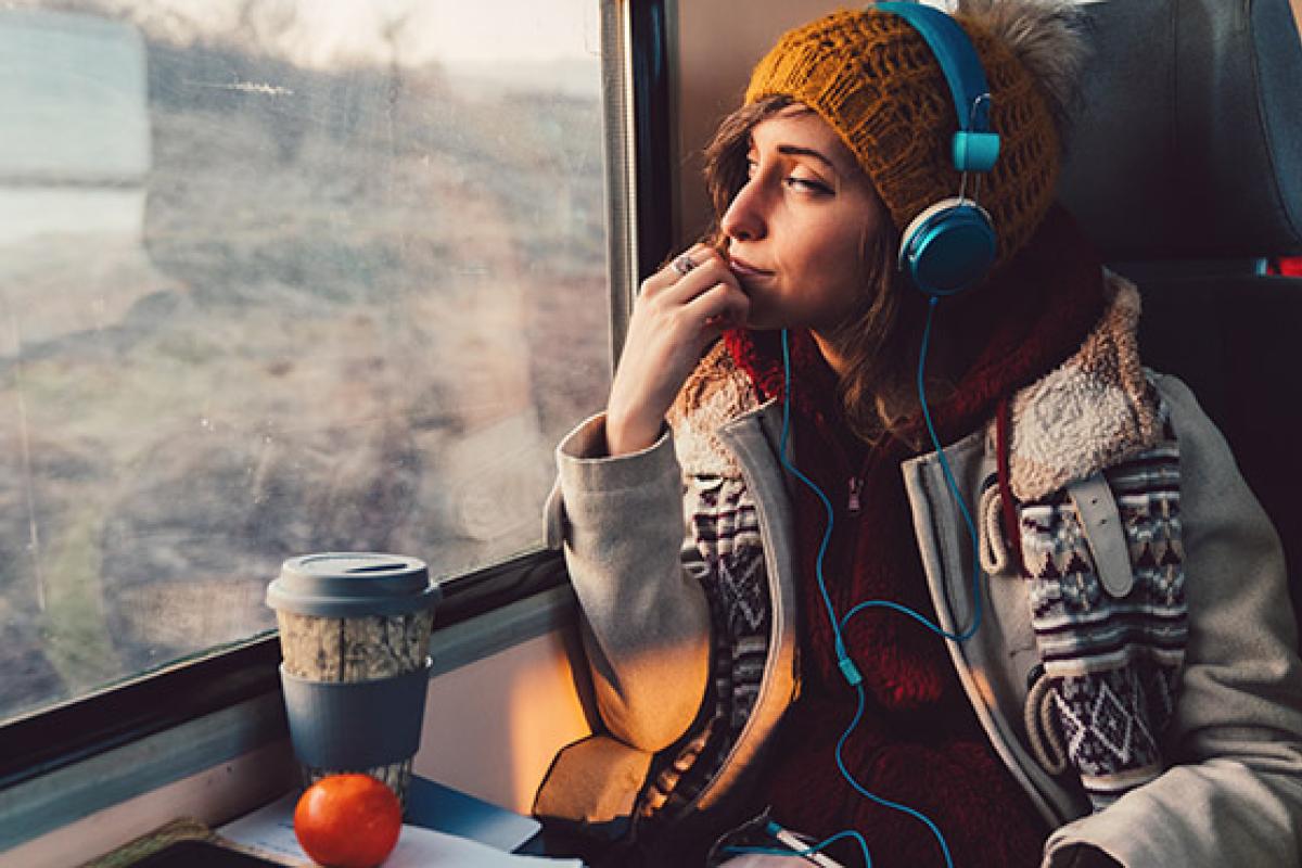 Young person sitting on a train listening to music