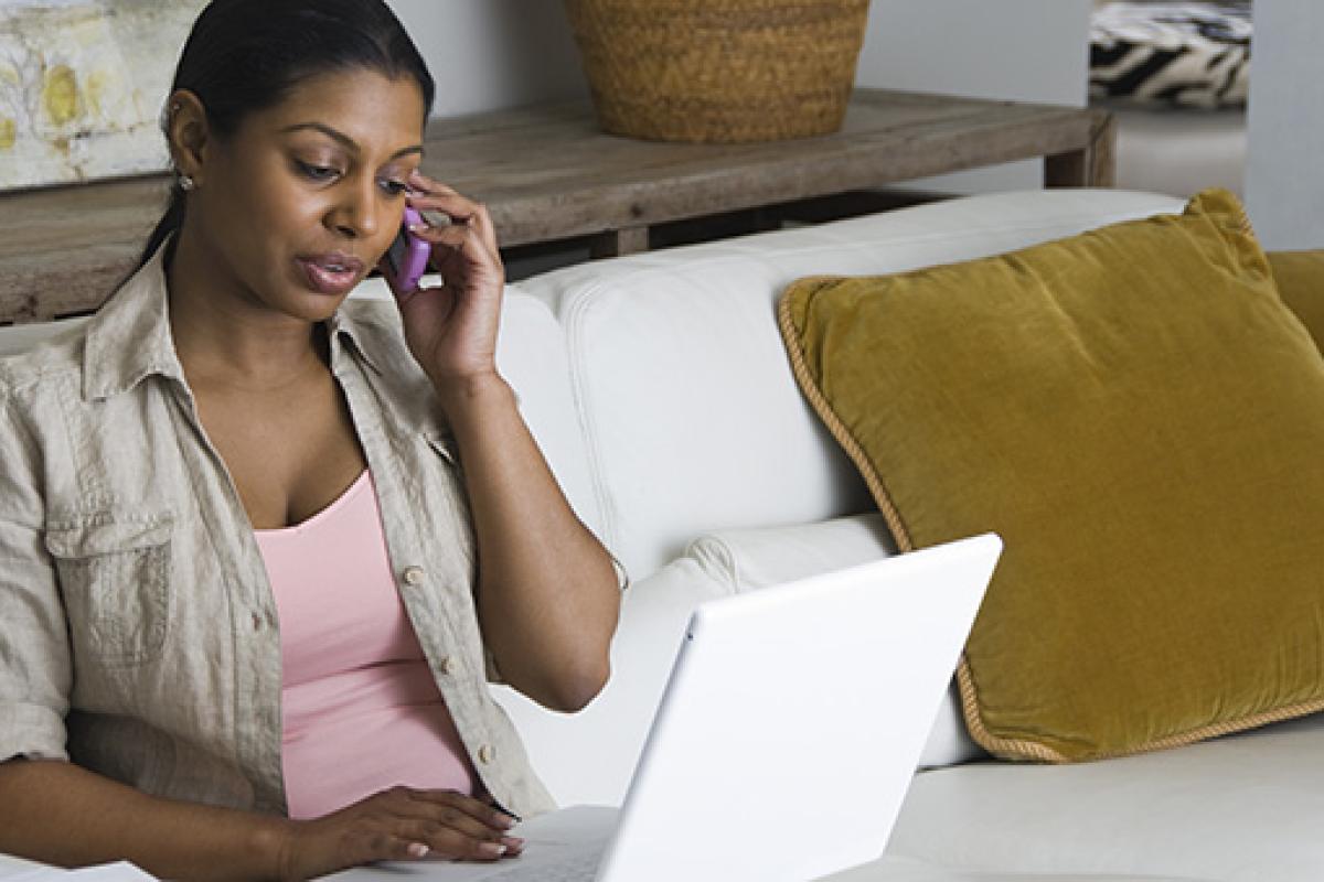 Person on the phone and looking at a laptop