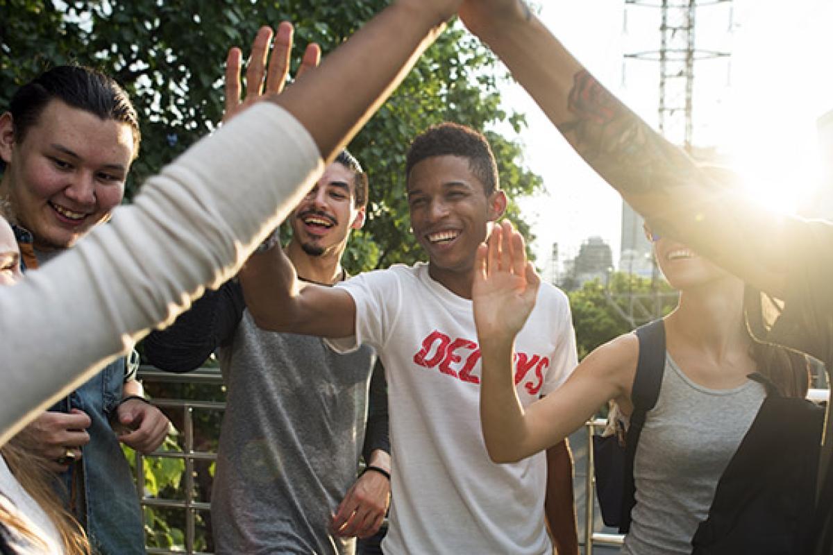 Group of young people smiling and giving each other high-fives