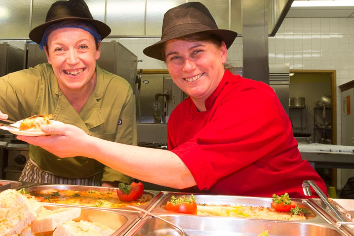 Two women serving food in school