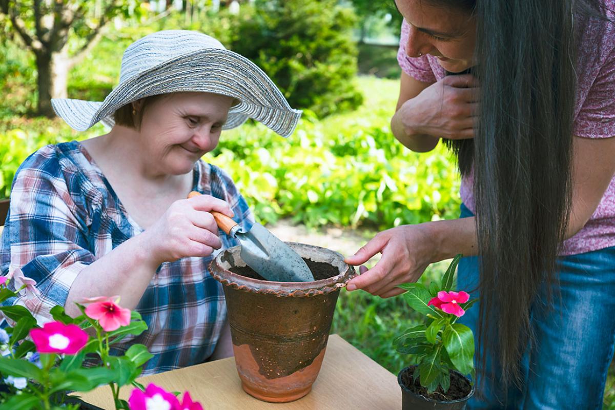 A woman with Down syndrome and her carer planting