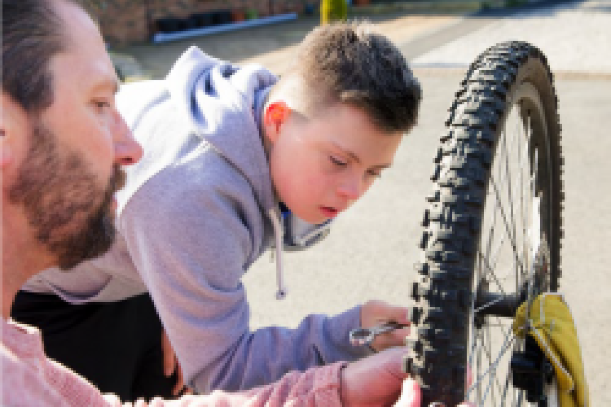 Teenage boy being shown how to look after a bike 